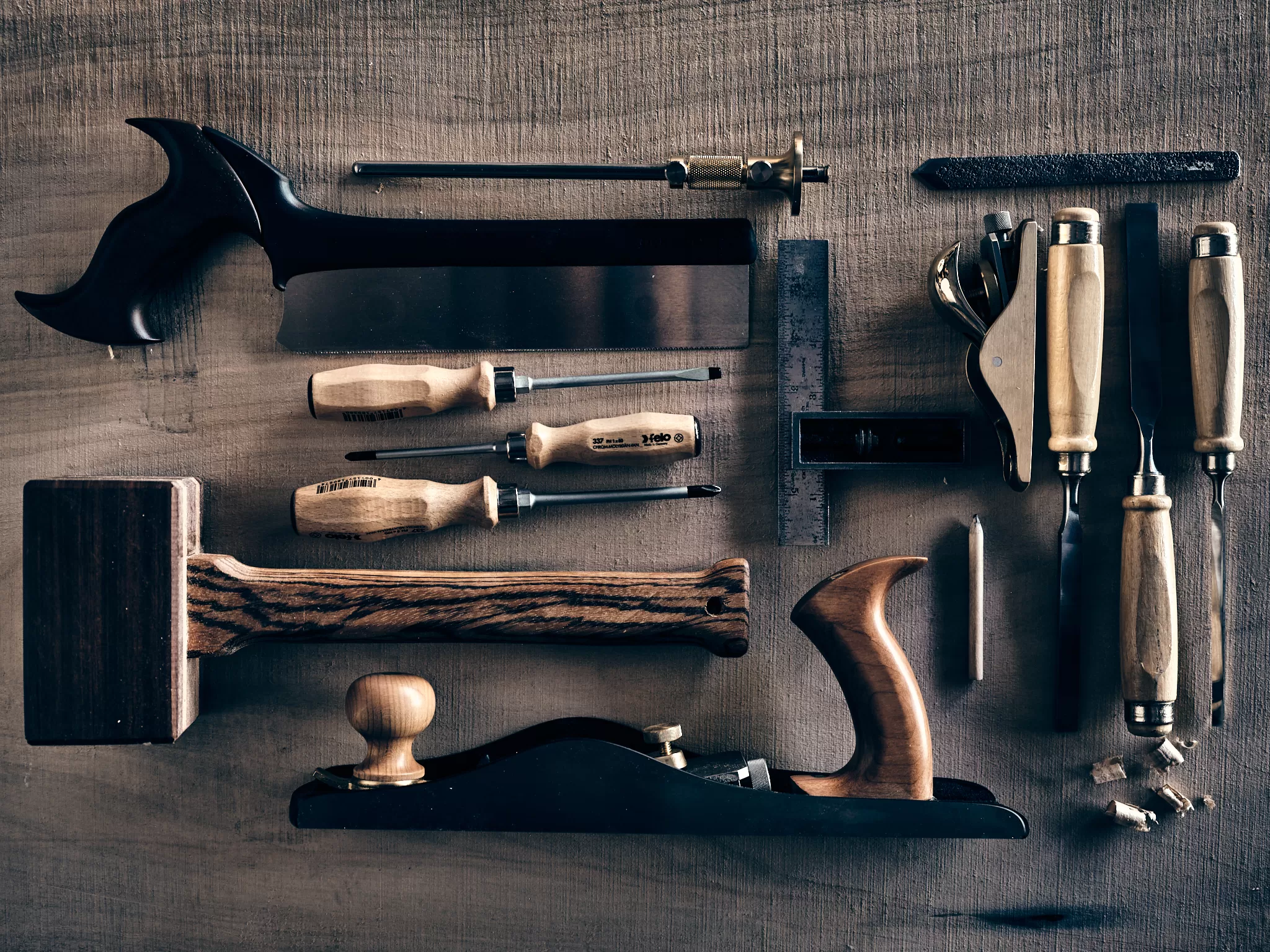 Traditional woodworking tools arranged on wood surface representing the craftsperson approach to AI collaboration workflow: hand planes, chisels, squares, and precision instruments that mirror the thoughtful methodology of building knowledge like crafting a bureau.